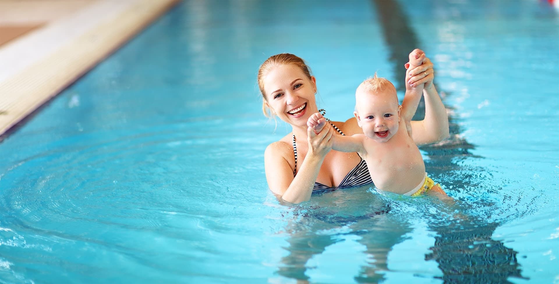 Mutter mit Baby fröhlich im Pool